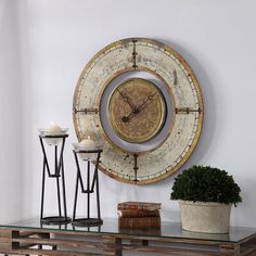 a clock mounted to the side of a wall next to a table with two candles