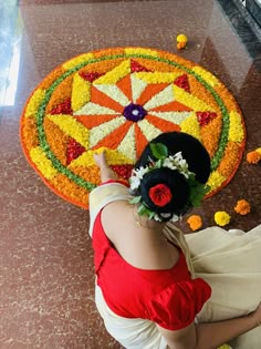 a woman sitting on the ground in front of a flower arrangement