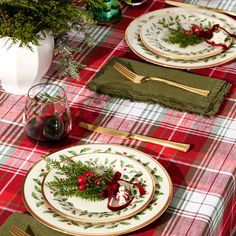 the table is set for christmas dinner with green napkins and red plaid place mats