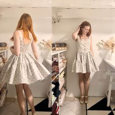 a woman standing in front of a mirror wearing a dress with flowers all over it