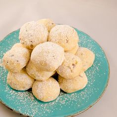 a blue plate topped with powdered sugar covered doughnuts on top of a table