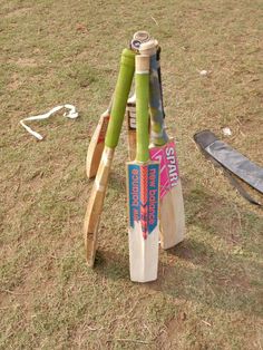 several wooden cricket bats are stacked on top of each other in the middle of a field