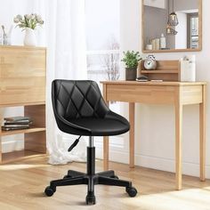 a black office chair sitting on top of a wooden floor next to a desk with a mirror