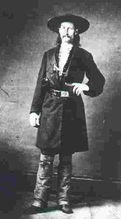 an old black and white photo of a man wearing a hat, long coat, and boots