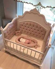 a baby is laying in a crib with pink and white furniture on the floor