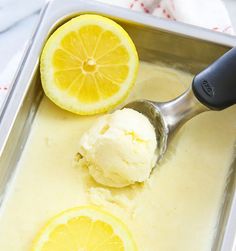 a scoop of ice cream with two lemons on the side and a spoon in it