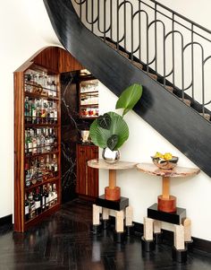 a table with two stools under a stair case