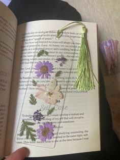 an open book with flowers on it and a tassel hanging from the front cover