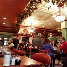 people sitting at tables in a restaurant decorated for christmas