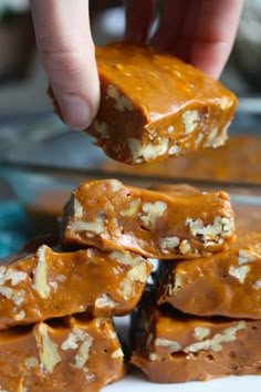 a person is picking up some kind of peanut butter fudge from a white plate