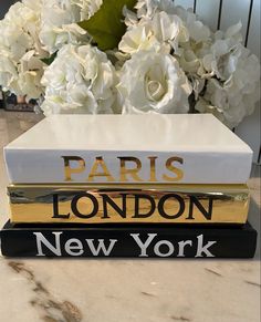 three books stacked on top of each other in front of white flowers and a marble table