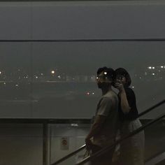 two people walking up an escalator with the city lights in the background