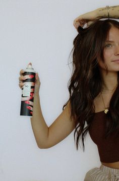 a woman holding a hair spray in her hand