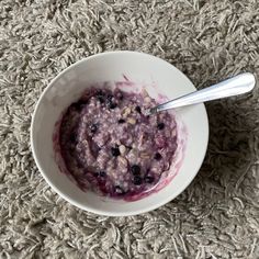 a bowl of oatmeal with blueberries and nuts in it on the floor