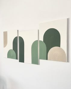 three green and white paintings hanging on the wall