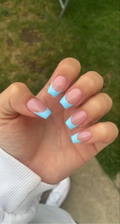 a woman's hand with some blue and pink nail designs on her nails,