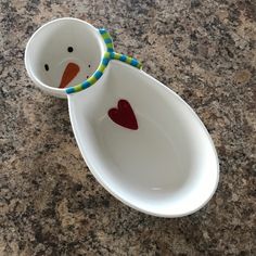 a white bowl with a red heart in the middle and a snowman face on it