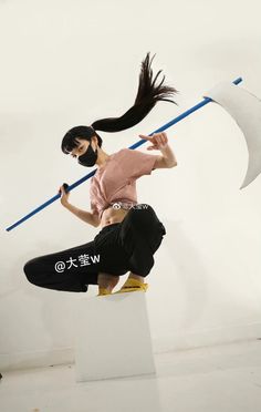 a woman with long black hair is performing on a skateboard and holding a pole