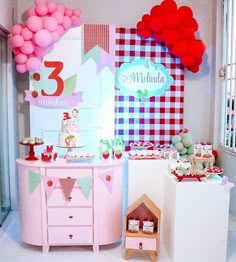 there is a pink dresser with balloons on it and other items in front of the wall