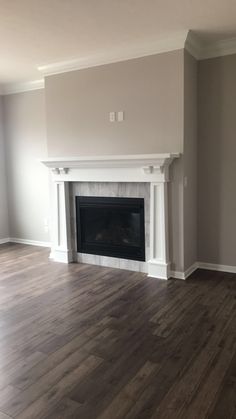 an empty living room with a fireplace and hard wood flooring in the middle of it