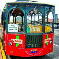 a red and green trolley on street next to curb