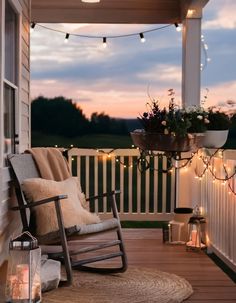 a rocking chair sitting on top of a wooden porch next to a lamp and potted plant