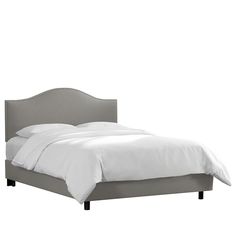 an upholstered bed with white sheets and pillows