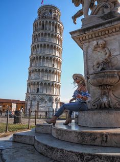 a woman sitting on top of a stone bench next to a tall tower