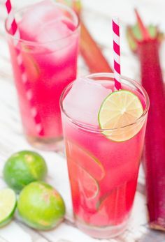 two glasses filled with pink lemonade next to limes and celery sticks