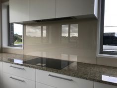 an empty kitchen with white cabinets and granite counter tops in front of a large window