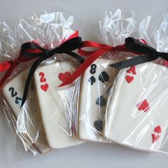 four decorated cookies wrapped in plastic and tied with red ribbon on white tablecloth, sitting next to each other