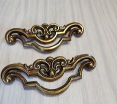 two antique brass drawer pulls on a white table