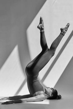 black and white photograph of a woman in leotard stretching her legs up on the floor