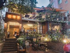 an outdoor restaurant with stairs leading up to the building and people sitting at tables outside