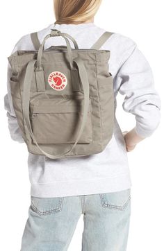 Find FJALLRAVEN Kånken Tote Backpack on Editorialist. The Fjällräven Kånken Tote Backpack is a classic design with a modern twist. Originally created for Swedish school children in the 1970s, the backpack is now a popular choice for everyday use. This durable and water-resistant bag features a spacious main compartment, a top zip closure, and a variety of pockets. The tote-inspired silhouette allows for easy access to your belongings, while the adjustable straps make it comfortable to carry. The backpack also includes a padded compartment for electronic tablets and a top handle for carrying by hand. The interior features wall pockets and the exterior includes both zip and slip pockets. Fjällräven Kånken, School Children, Wall Pockets, Fjallraven Kanken, Tote Backpack, Easy Access, Top Handle, Classic Design, 1970s