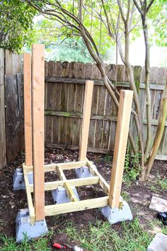 a wooden structure in the middle of a yard with tools around it and some trees