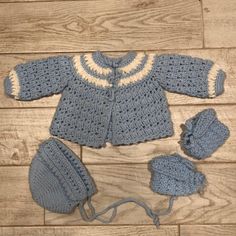 a crocheted blue sweater and hat with matching booties on a wooden floor