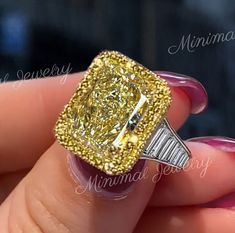 a woman's hand holding a ring with a yellow and white diamond in it