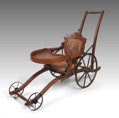 an old fashioned wooden baby carriage with wicker seat and footrests on wheels