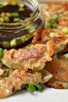 pork dumplings with steamed green onions and dipping sauce on the side, served in a glass jar