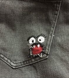 a pair of eyes on the back of a jean jacket with a red heart in the pocket