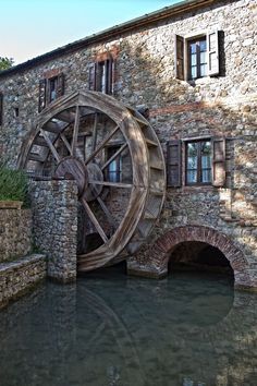 an old water wheel in front of a stone building