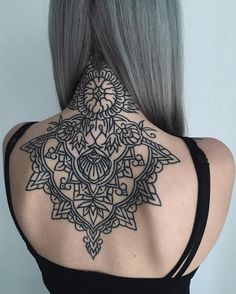 the back of a woman's neck with an intricate tattoo design on her shoulder