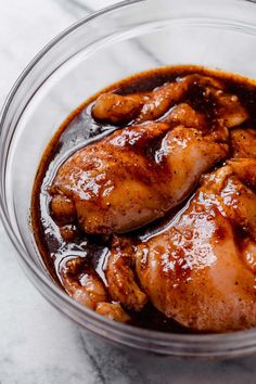 a glass bowl filled with chicken and sauce