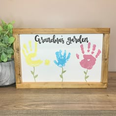 a wooden frame with handprints on it next to a potted plant