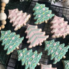 decorated christmas cookies sitting on top of a cooling rack next to snowflakes and pine cones