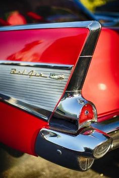 the tail end of an old red car with chrome lettering on it's hood