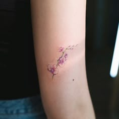 a woman's arm with a small flower tattoo on the left side of her arm