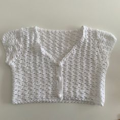 a white knitted sweater sitting on top of a table