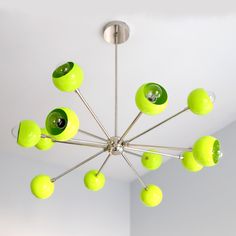 a green chandelier hanging from the ceiling in a room with white walls and flooring